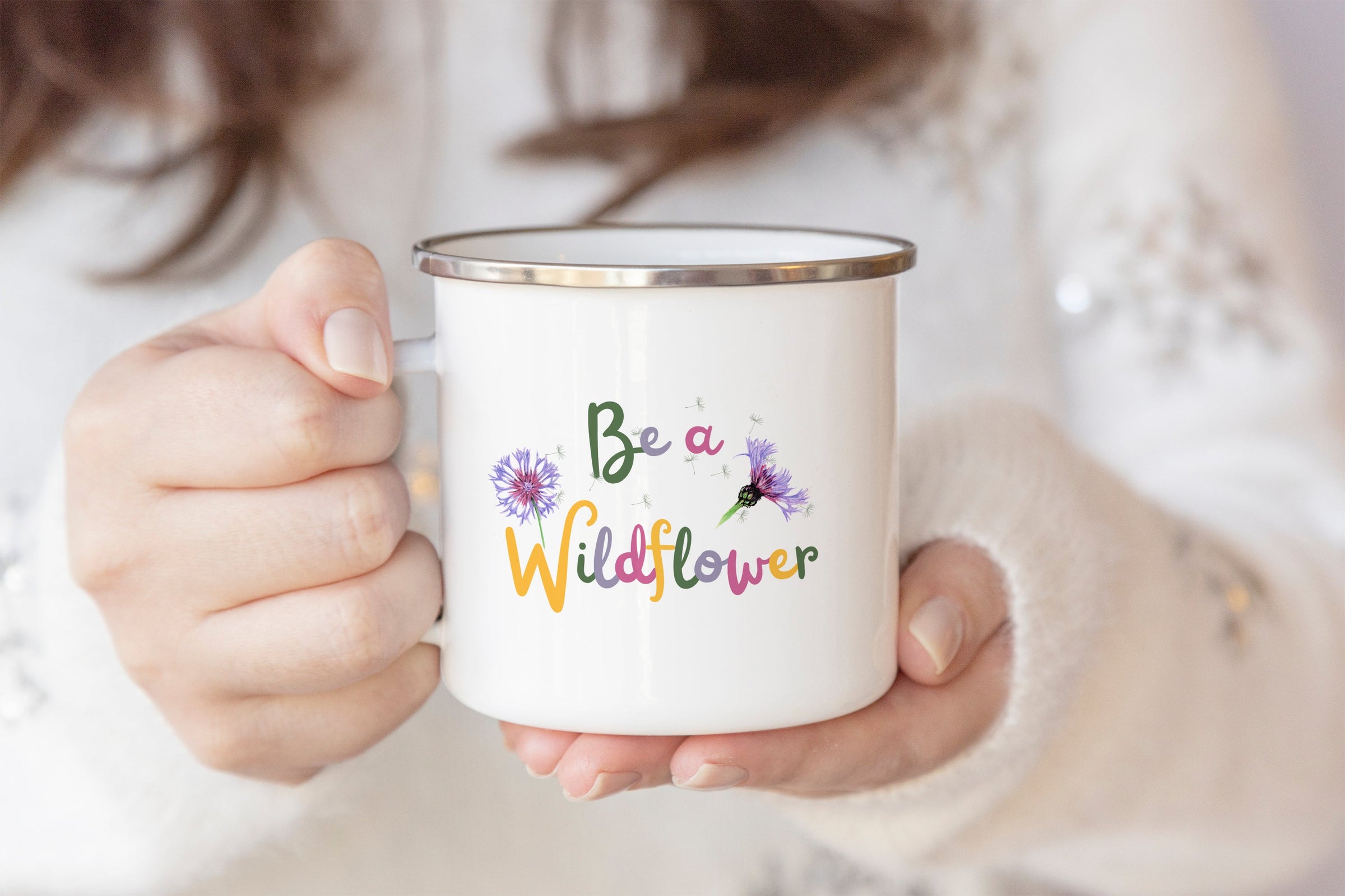 Woman holding 'Be a Wildflower' enamel mug with botanical design