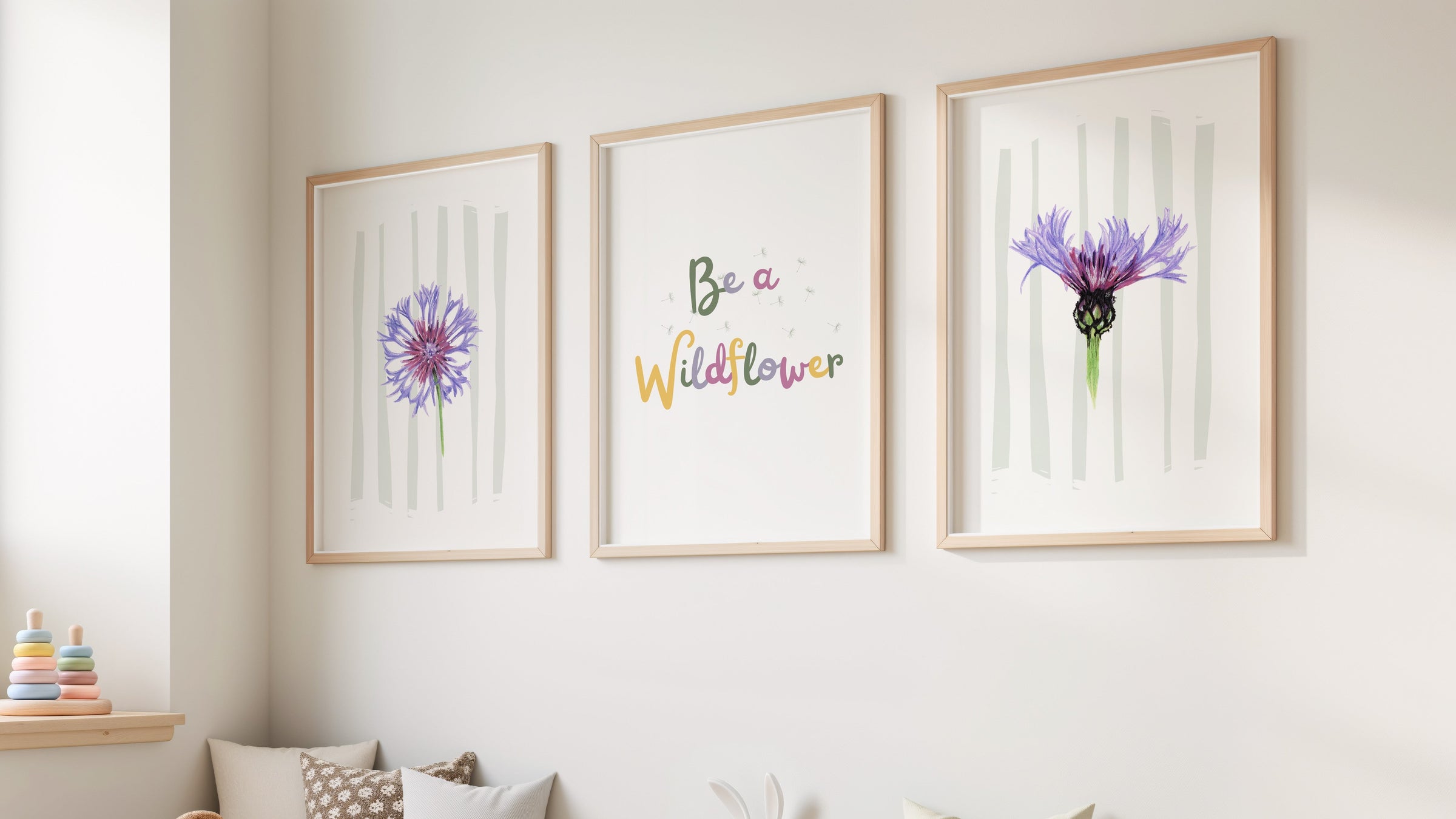 Three framed wildflower prints from the 'Be a Wildflower' collection hanging on the wall of a bright nursery
