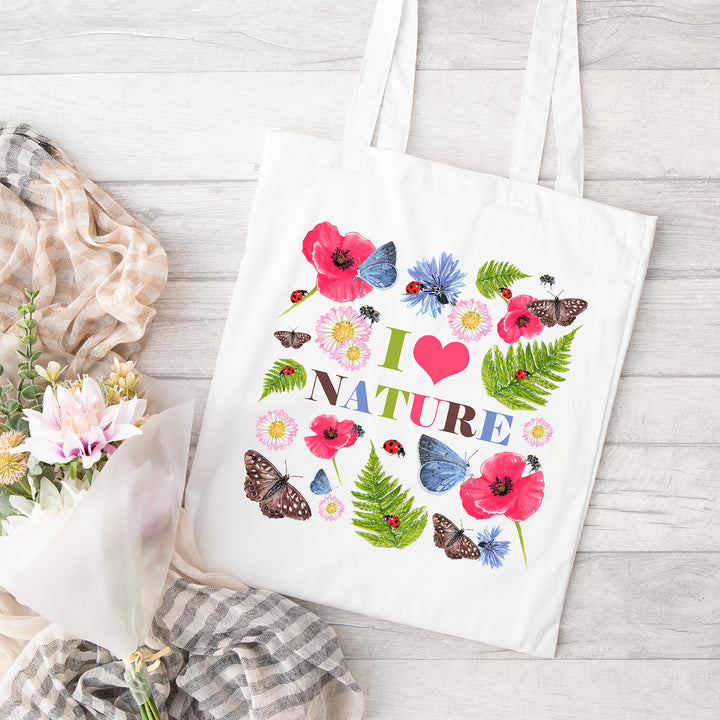 Cotton white shopper bag on a pale grey wooden background with a "I Love Nature" design