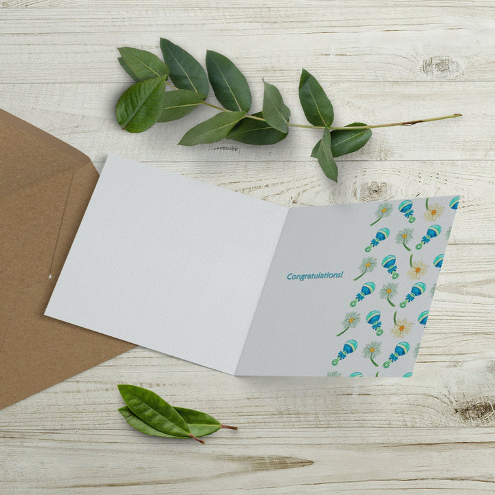 Inside of gender-neutral baby card, featuring a green watercolour flower and rattle design with a “Congratulations” message. Printed on sustainable paper, supporting wildlife charities.