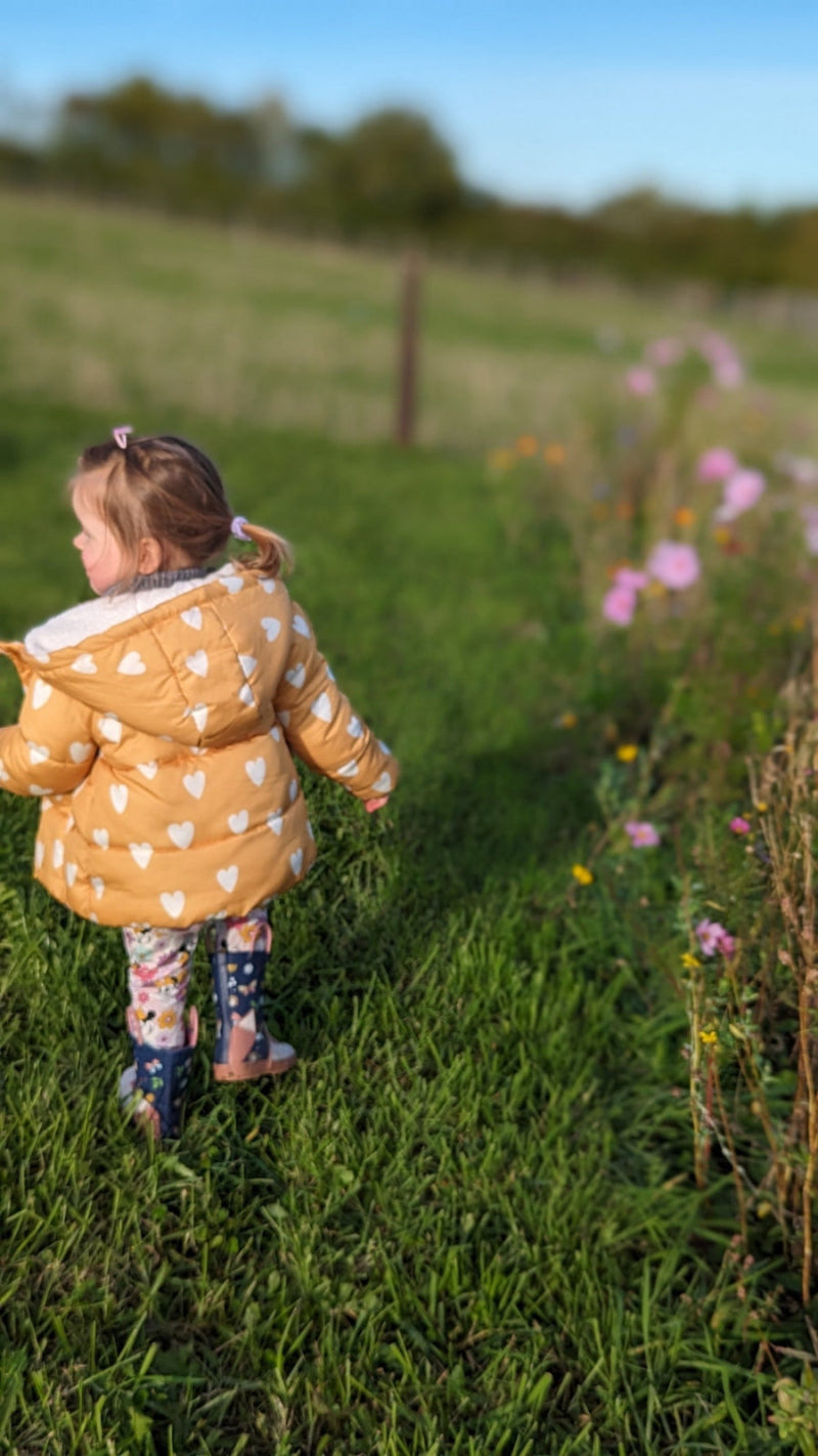 Layla enjoying nature next to wildflowers, reflecting the eco-friendly and wildlife-loving ethos of my nature-inspired designs for children's décor and product licensing