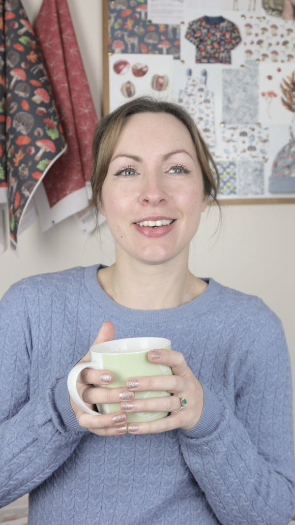 Emma in her studio with a cup of tea, surrounded by her nature-inspired design board filled with wildlife and animal sketches—perfect for licensed product design and brand collaborations.