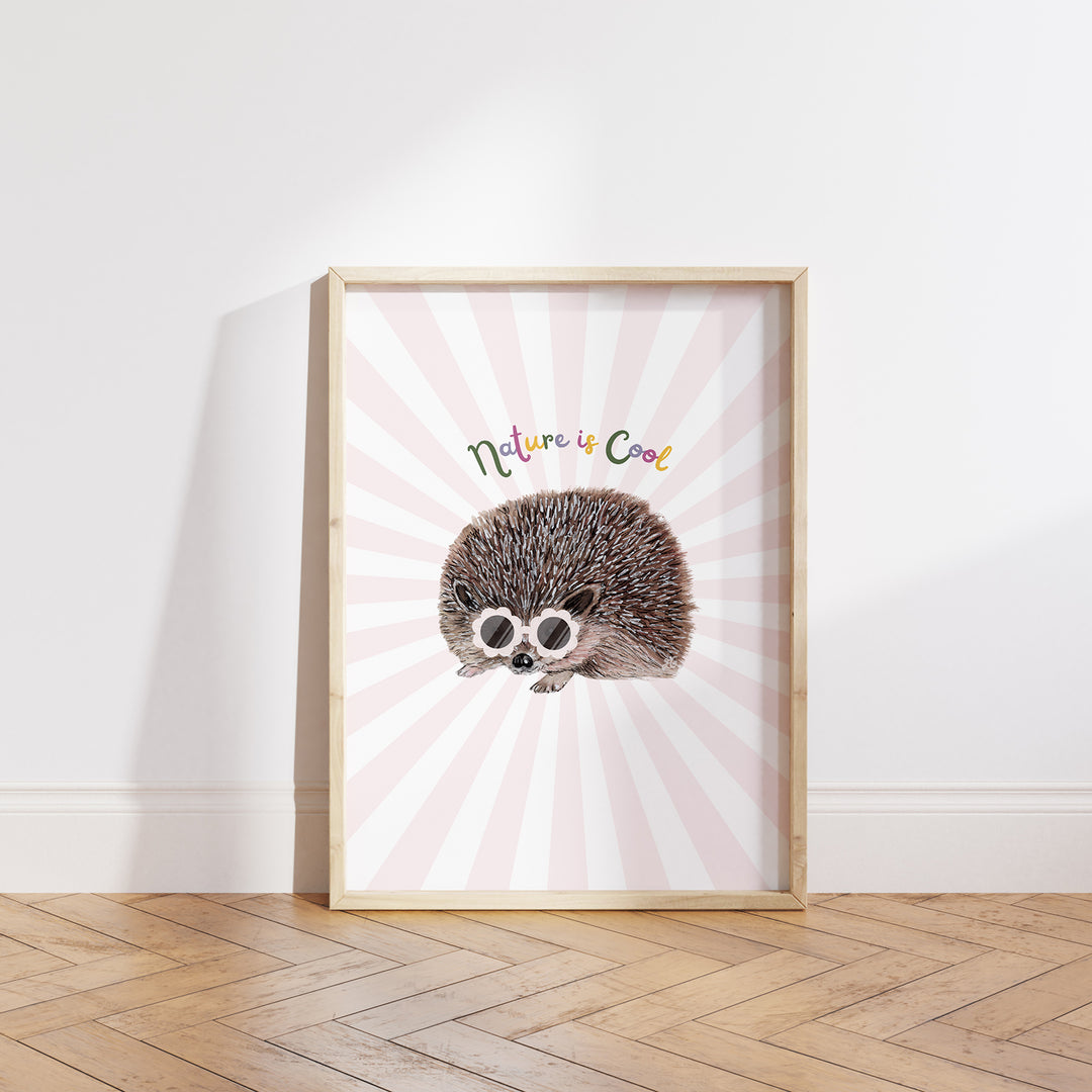 Hand-drawn hedgehog wearing pink sunglasses with “Nature is Cool” text on a pink and white sunburst background, framed as a giclée art print.
