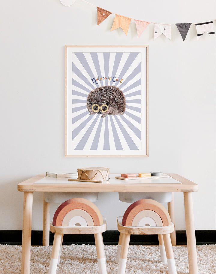 "nature is cool" art print framed and on wall of child's playroom desk. The print is of a hedgehog against a blue starburst.