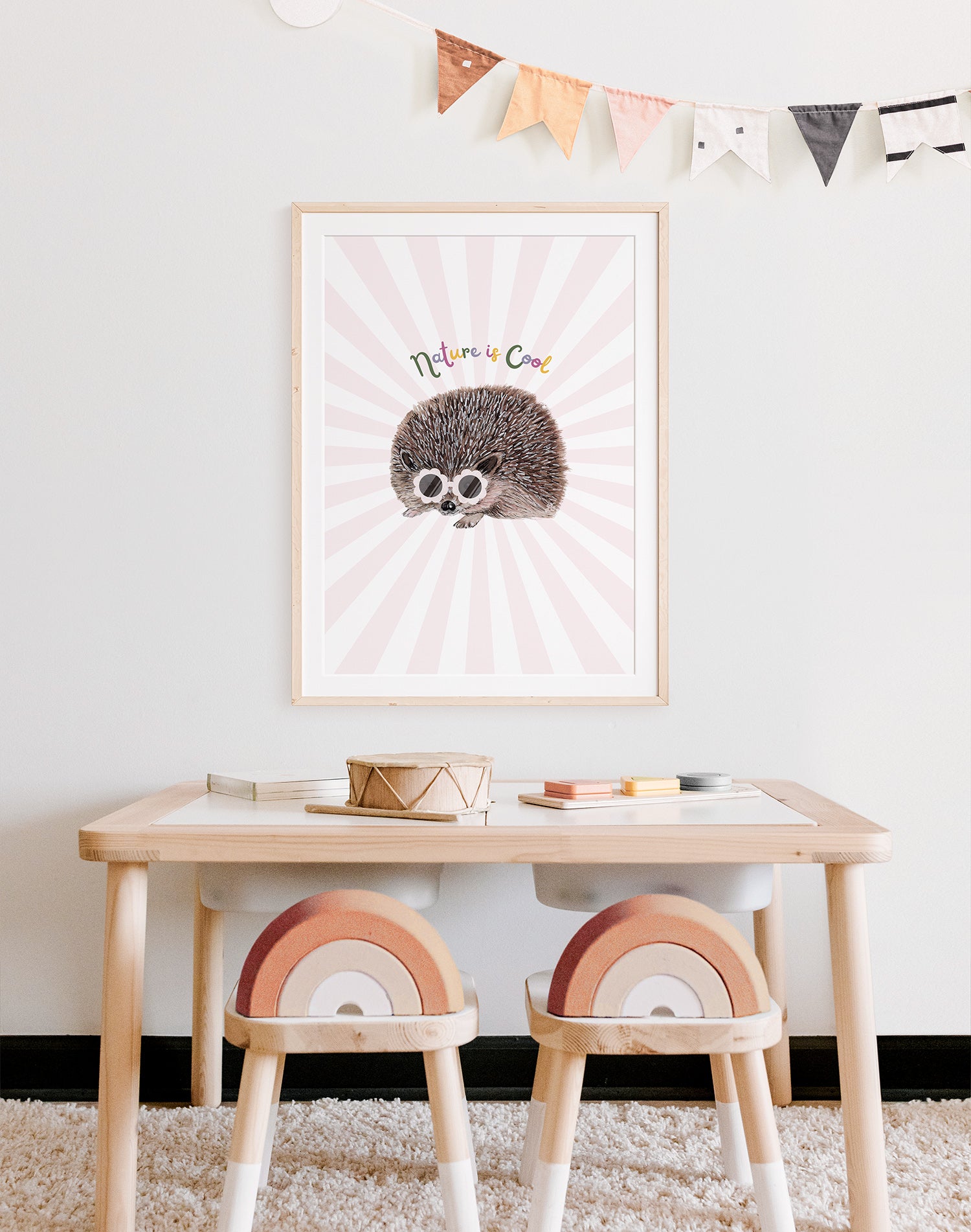 "nature is cool" art print framed and on wall of child's playroom desk. The print is of a hedgehog against a pink starburst.
