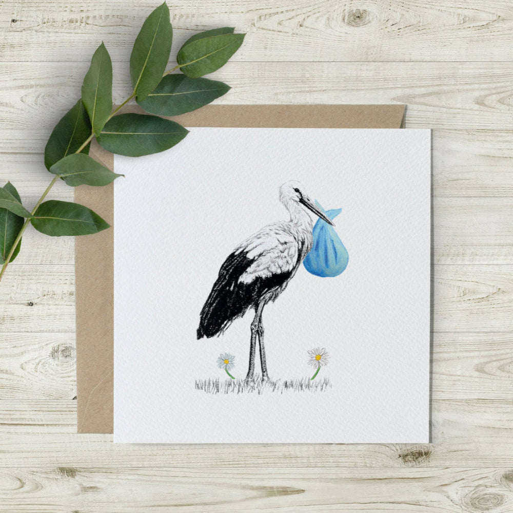 New baby boy card featuring a hand-drawn stork carrying a blue cloth bundle, printed on eco-friendly textured paper. A percentage of sales supports wildlife charities.