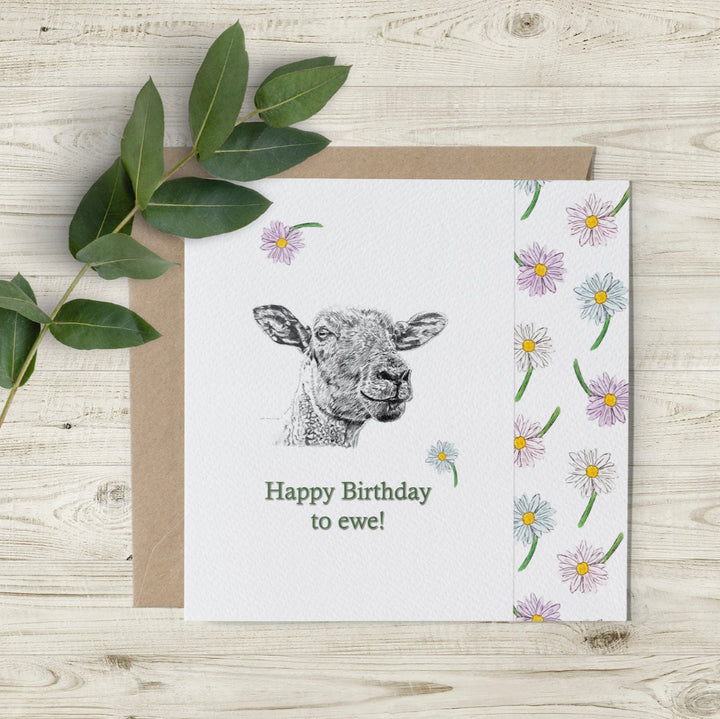 Eco-friendly sheep birthday card with "Happy Birthday to Ewe" and soft pastel daisies, hand-drawn and UK-made by Emma Gorton-Garlick.