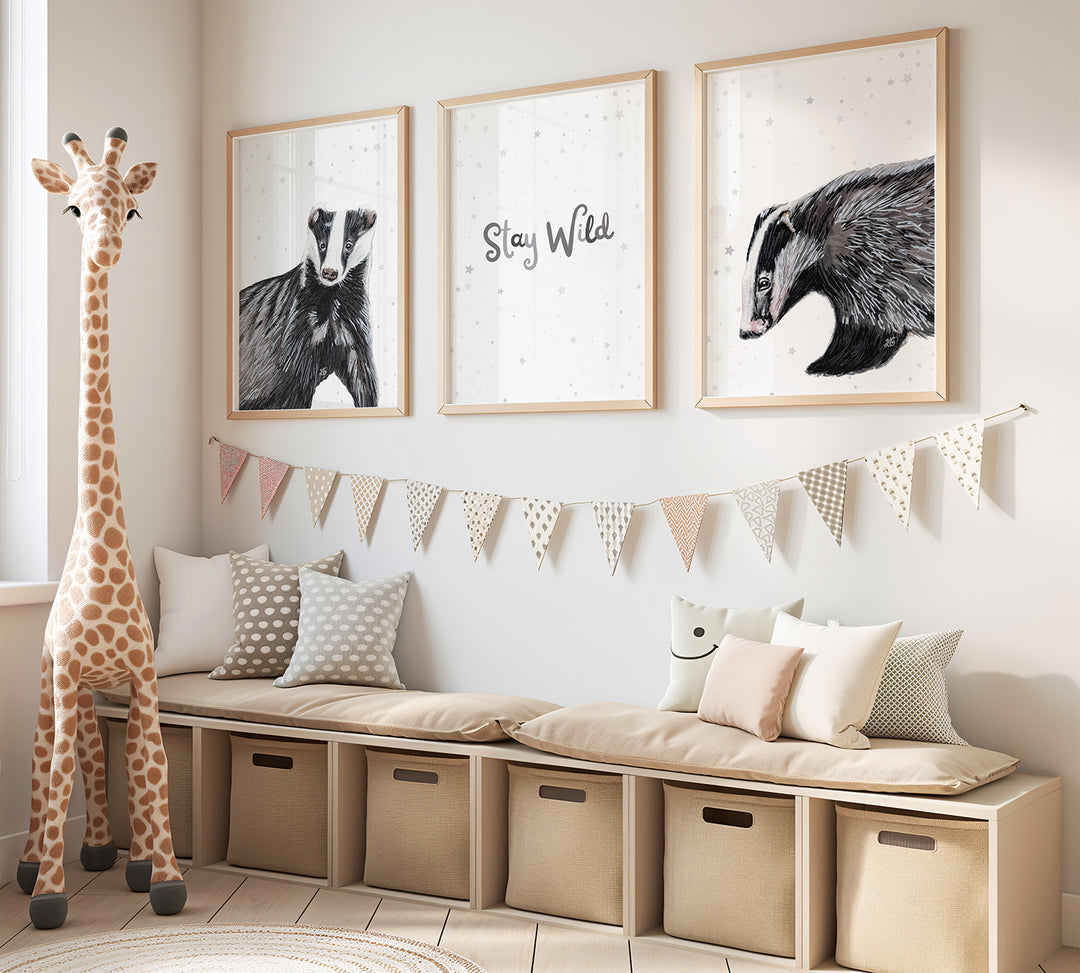 child's bedroom with large soft toy giraffe and art print set on the wall - two badgers against a grey starry background on either side of a print saying "stay wild"