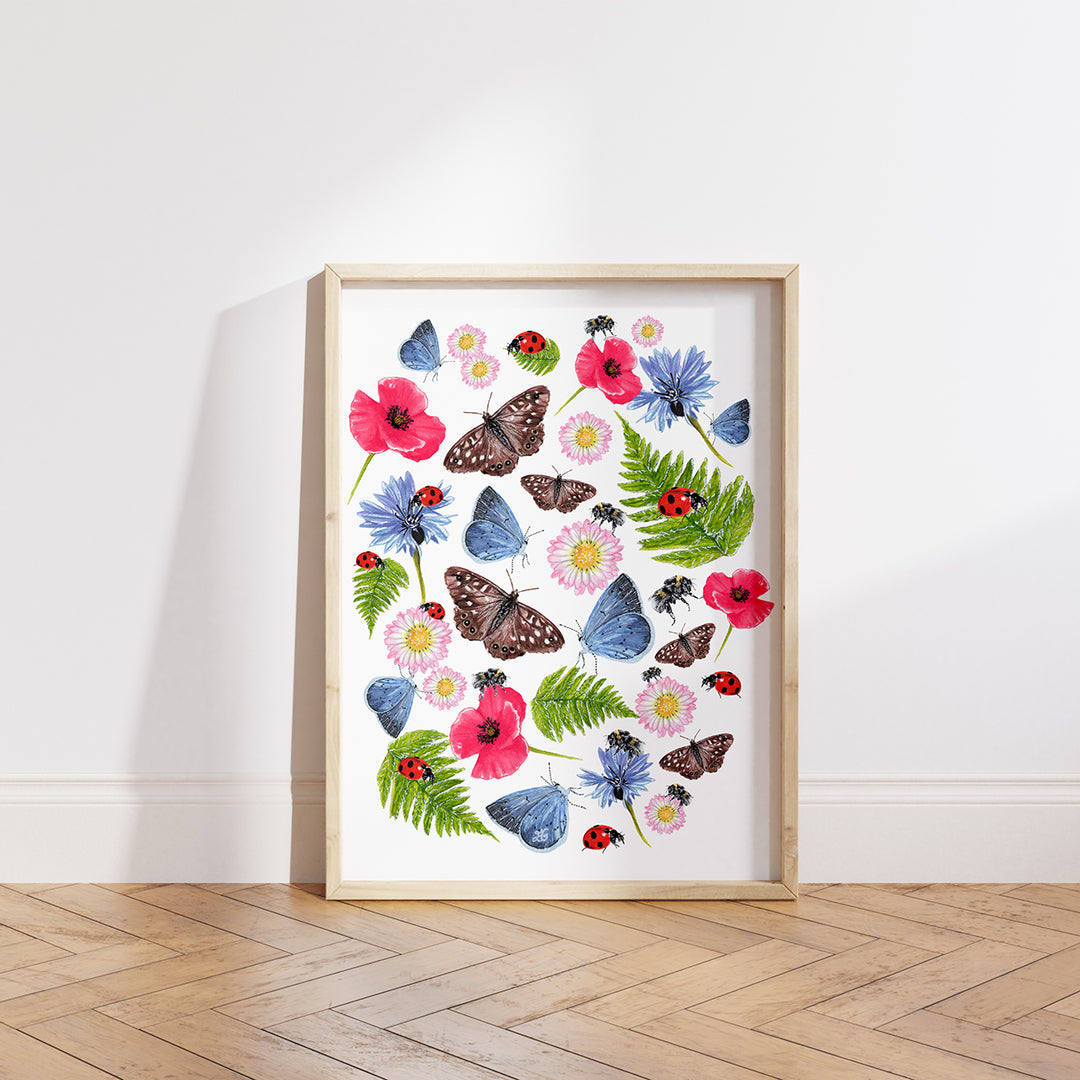 Summer Meadow giclée print framed in a pale wooden frame, displayed on a wooden floor against a white background, featuring bees, butterflies, wildflowers and insects