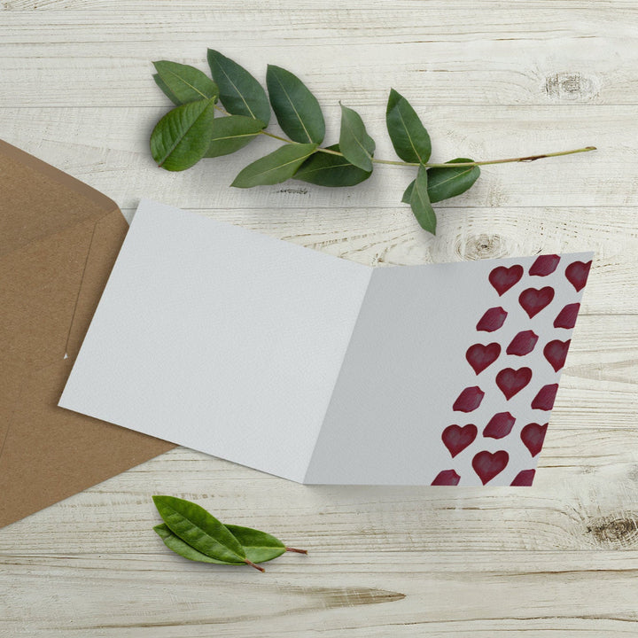 Inside of eco-friendly Valentine’s Day card with a cutaway edge revealing red watercolour hearts and petals. Sustainably printed in the UK.